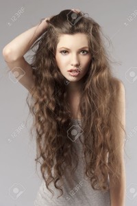 9645274-giovane-ragazza-carina-capelli-lunghi-ricci-in-un-porteait-su-sfondo-grigio-Archivio-Fotografico